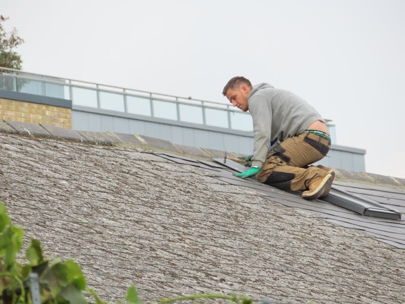 Roofer placing tiles during roof repair